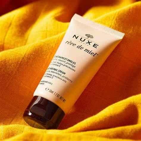 Crema mani Nuxe Rêve de Miel tubetto 50ml su tessuto giallo, cosmetico idratante mani.
