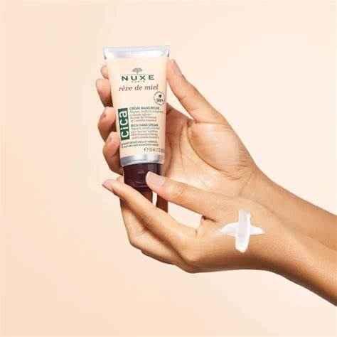 Crema mani Nuxe Reve de Miel Cica su mano con texture visibile, cosmetico idratante.