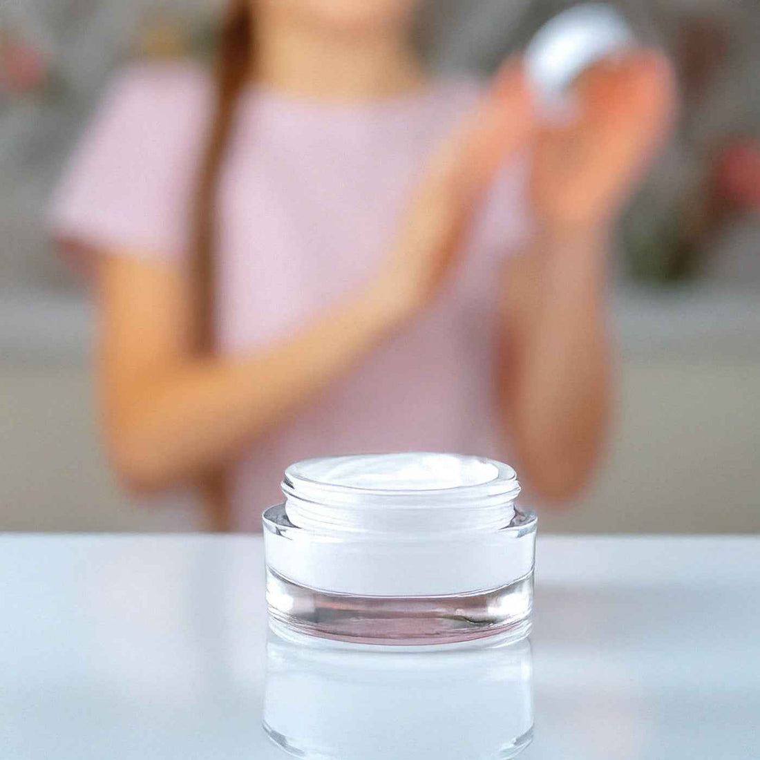 Vaso di crema viso cosmetica bianca su tavolo, applicazione prodotto skincare.