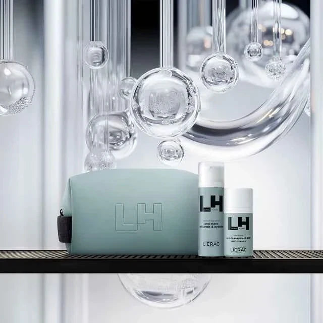 Set cosmetici Lierac LH uomo con beauty bag azzurra, flaconi su sfondo moderno con bolle trasparenti