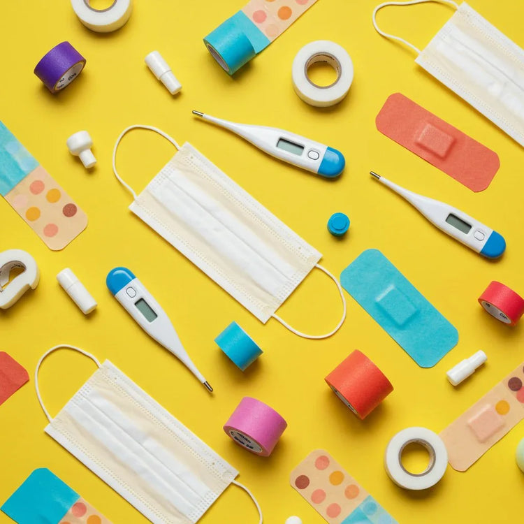 Dispositivi medici: mascherine, termometri digitali, cerotti e nastri colorati su sfondo giallo.