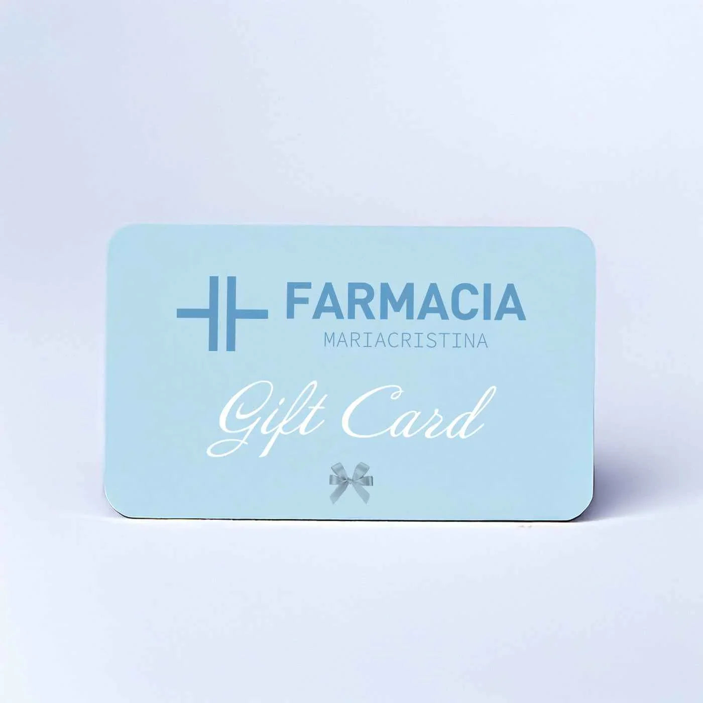 Gift card azzurra di farmacia con scritta, simbolo croce e fiocco, su sfondo chiaro.
